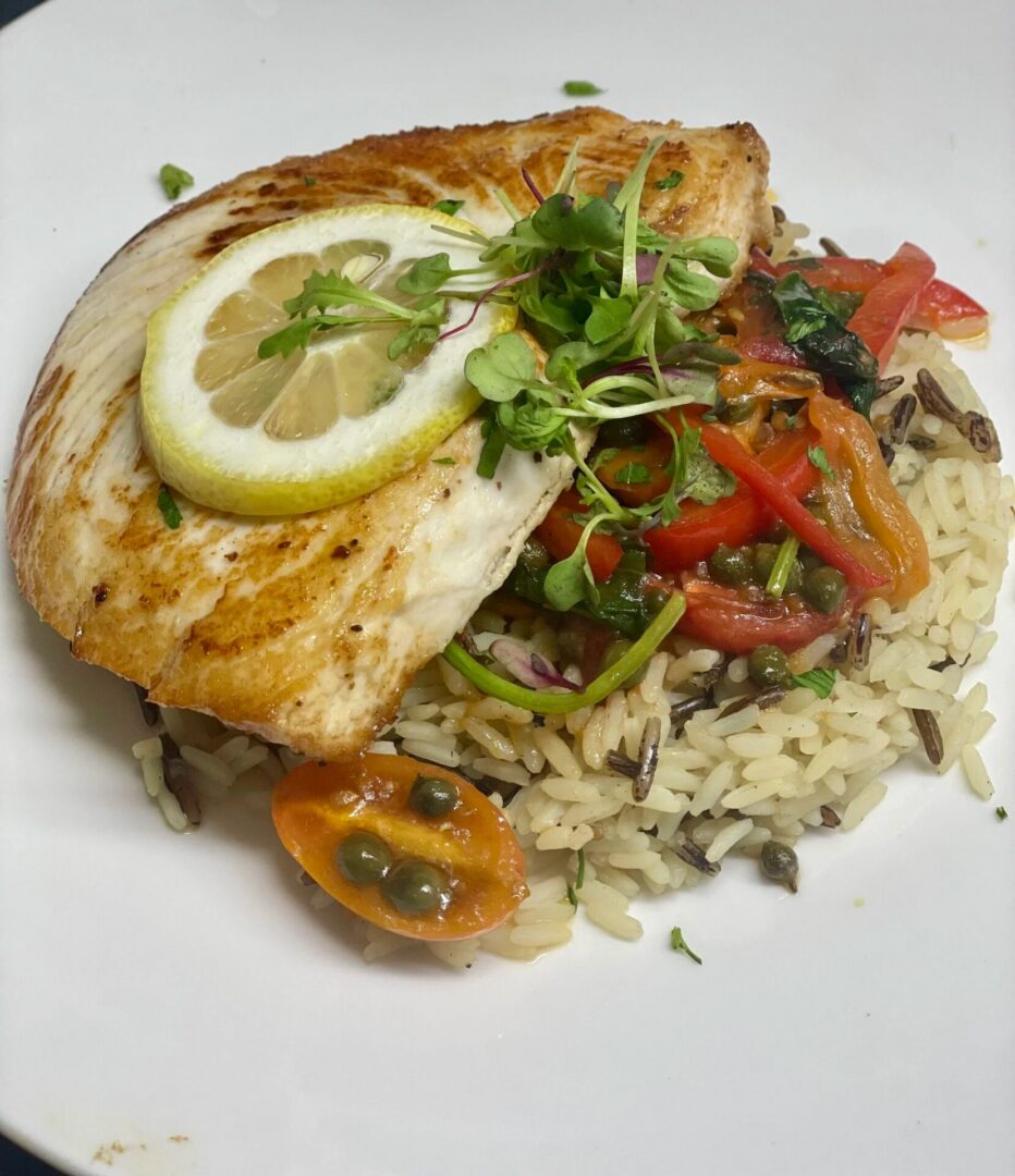 White plate topped with a piece of fish and a side of rice