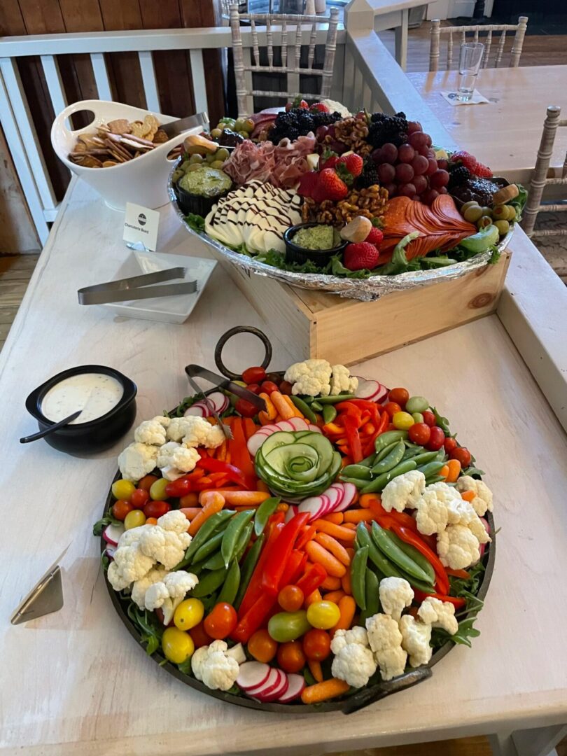 Table with a platter of food on top of it, surrounded by chairs and a railing